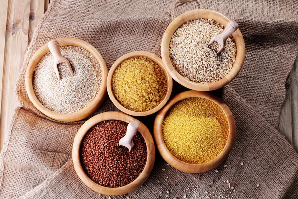 Various groats set in wooden bowls — Stock Photo, Image