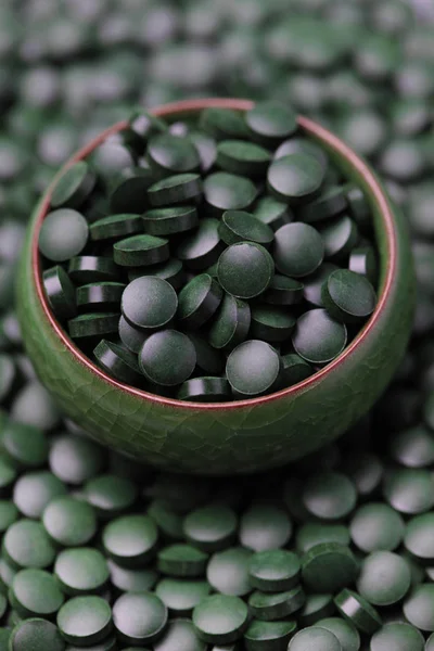 Pílulas de spirulina em tigela verde — Fotografia de Stock