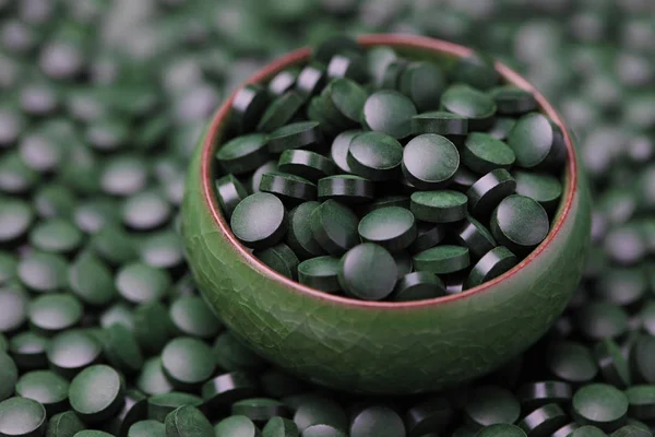 Piller af spirulina i grøn skål - Stock-foto