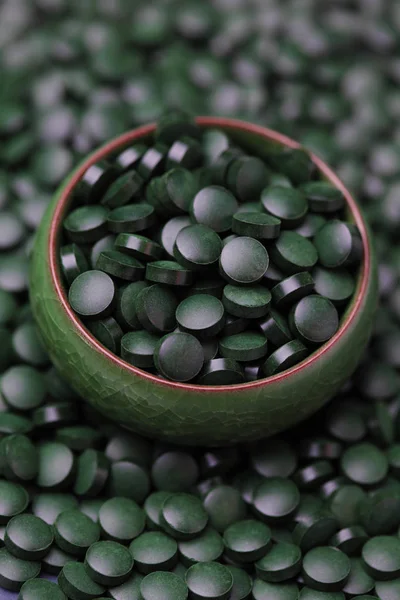 Pills of spirulina in green bowl — Stock Photo, Image