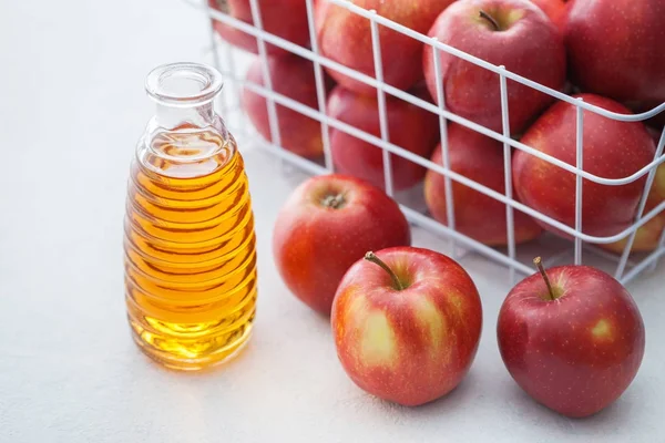 View of apple vinegar bottle with apples on white table