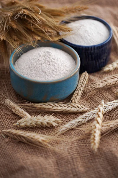 blue bowls of flour with wheat ears on burlap background