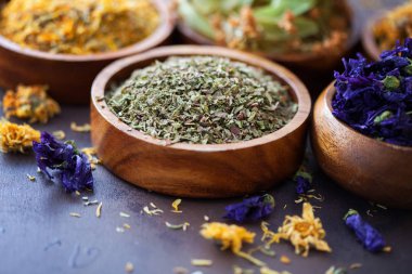 Natural alternative herbal medicine of dried herbs and flowers in wooden bowls, selective focus clipart