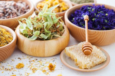 close up of wooden bowls with herbs and tea on white table with copy space clipart