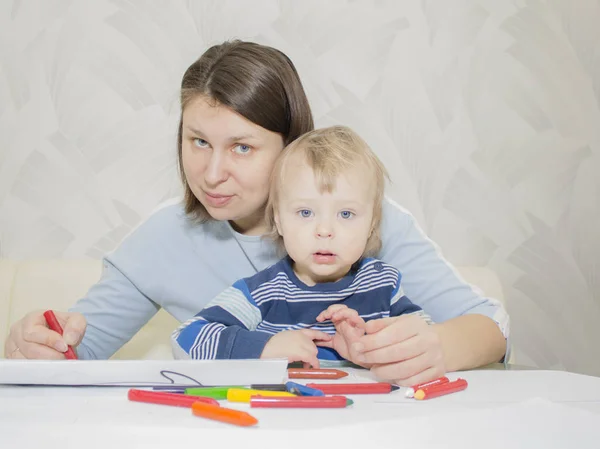 Mor och son drar tillsammans med pennor på bord — Stockfoto