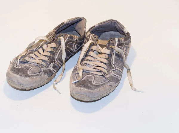 very old running shoes with laces on a light background.