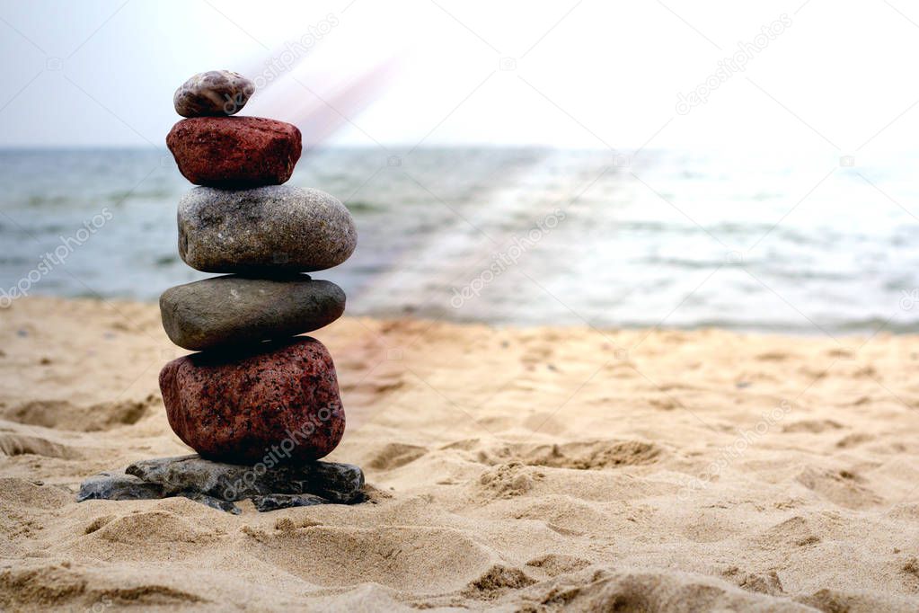 Pyramid of the stones on the sandy beach at ocean background