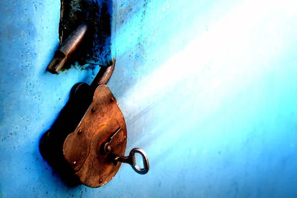 Stary zardzewiały blokada z kluczem na niebieskim tle — Zdjęcie stockowe