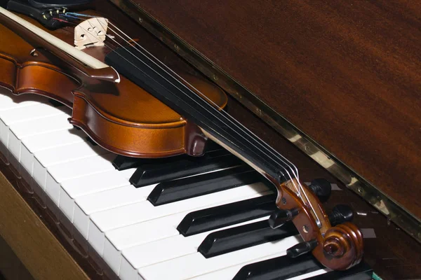 Mycket gammal fiol liggande på piano — Stockfoto