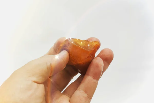Amber in the hand with a bright reflection on the palm against the background of the sea. — Stock Photo, Image
