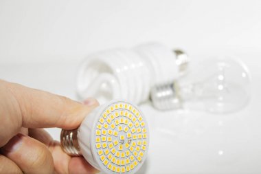 Birkaç farklı led ampuller ve kompakt floresan lambalar ve erkek eli hafif bir arka plan üzerinde.