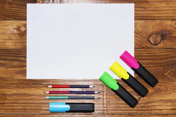 종이의 흰 시트 연필, 마커, 펜, 근처 나무 테이블에 누워. 위에서 보기. — 스톡 사진