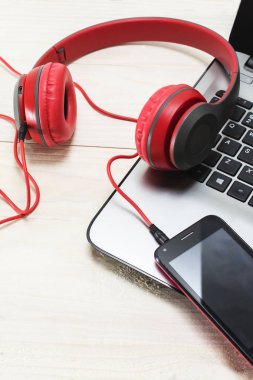 açık renkli laptop ve kırmızı ahşap kulaklıklar.