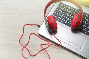 açık renkli laptop ve kırmızı ahşap kulaklıklar.