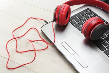 açık renkli laptop ve kırmızı ahşap kulaklıklar.