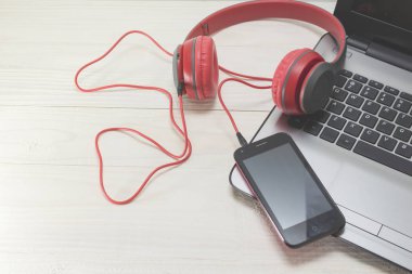 açık renkli laptop ve kırmızı ahşap kulaklıklar.