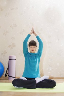 Genç güzel atletik kız avuç içi Namaste, yarım Lotus duruş ile Ardha Padmasana oturan kapalı yoga uygulamak.
