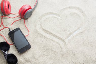 telefon ile kulaklık ve bir yaz plaj kum üzerinde güneş gözlüğü