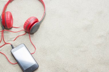 yaz plaj kum üzerinde kulaklık ile telefon.