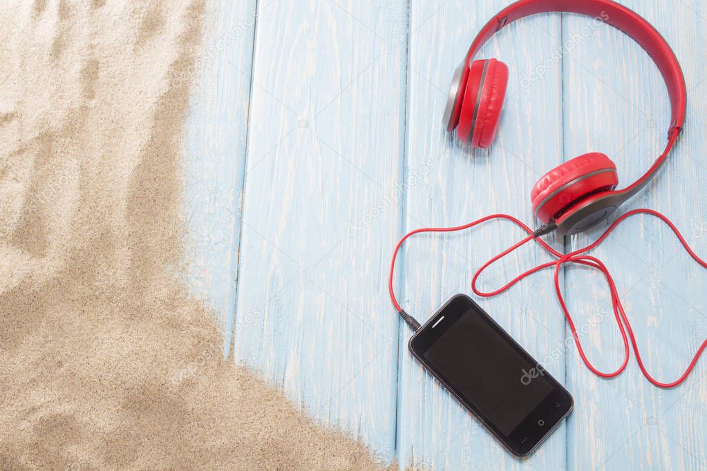 phone with headphones on sand in a summer beach.