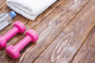 dambıl ve bir şişe su ahşap zemin, fitness spor aletleri için hazırlanıyor kavramı üzerine havlu ile görünümü top.