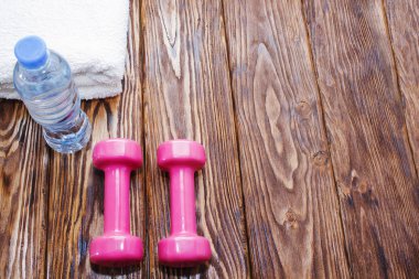 dambıl ve bir şişe su ahşap zemin, fitness spor aletleri için hazırlanıyor kavramı üzerine havlu ile görünümü top.