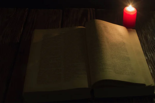 Vela e um livro da Bíblia sobre fundo de madeira à noite — Fotografia de Stock