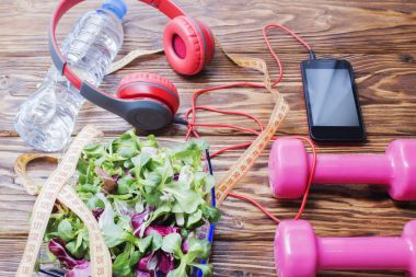 Ahşap bir tezgah, kopya alanı, diyet ve sağlıklı beslenme kavramı dumbbells ile taze organik sebze. Kulaklık ve telefon. Müzik spor