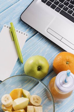 Dizüstü, bilgisayar, defter, kalem, marker ile çalışma masası. Yararlı güler yüzlü içki. Turuncu