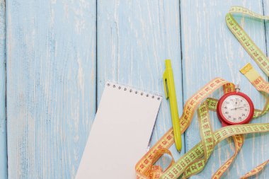 Terzi bir defter ve bir kronometre ile mavi bir arka plan üzerinde inç.