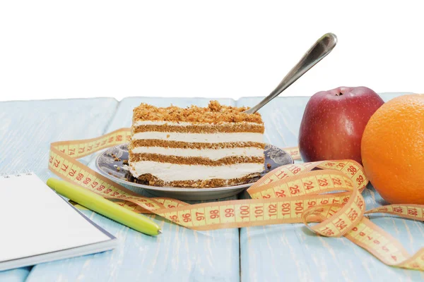 Концепция здорового питания, кусок торта на деревянном столе и измерительная лента с блокнотом и ручкой . — стоковое фото