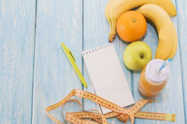 Diyet, sağlıklı ve aktif yaşam tarzı kavramı, elma, muz, git, mezura, suyu şişesi, boş kopya alanı ile boş bir not defteri en iyi görünüm.