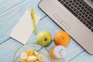 Dizüstü, bilgisayar, defter, kalem, marker ile çalışma masası. Yararlı güler yüzlü içki. Turuncu