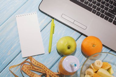 Dizüstü, bilgisayar, defter, kalem, marker ile çalışma masası. Yararlı güler yüzlü içki. Turuncu