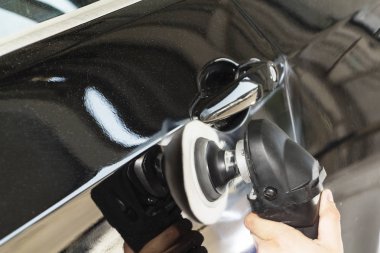 Araba tamiri, oto tamirhanesinde orbital parlatıcıyla el işi. Seçici odak.