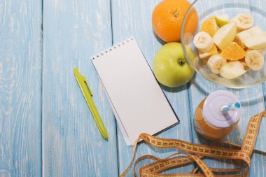 Diyet, sağlıklı ve aktif yaşam tarzı kavramı, elma, muz, git, mezura, suyu şişesi, boş kopya alanı ile boş bir not defteri en iyi görünüm
