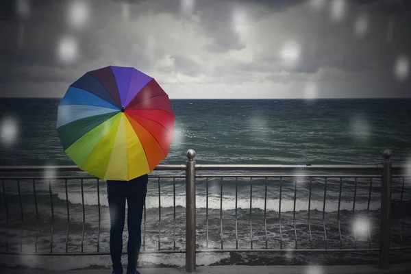 Giovane bella donna con ombrello colorato in pioggia e neve sul mare d'inverno o sullo sfondo dell'oceano — Foto Stock