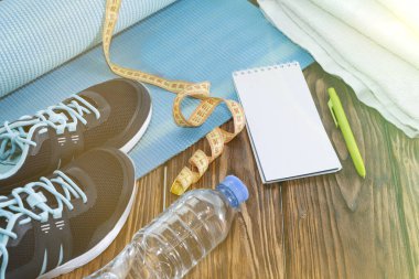 Sağlıklı yaşam ve spor arka plan. Spor ayakkabı, not defteri ve kalem, kronometre ve su şişesi boşaltmak, ahşap zemin üzerine görünümü top.