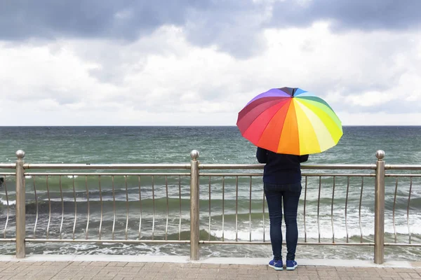 Jovem mulher bonita com guarda-chuva colorido na chuva no fundo do mar ou do oceano — Fotografia de Stock