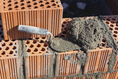 Spatula ve çimento harcı, kırmızı tuğla duvar, inşaat konsepti.
