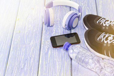 Spor malzemeleri. Spor ayakkabıları, su ve kulaklık, arka planda.