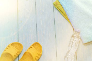 Şişe su ve parlak havlu, mavi zemin üzerine sarı şeyl.