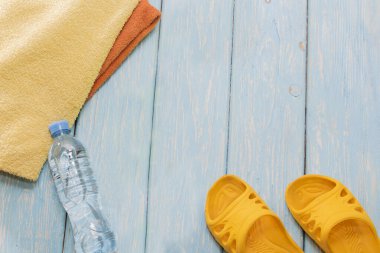 Şişe su ve parlak havlu, mavi zemin üzerine sarı şeyl.