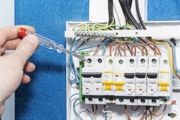 Mano de un electricista con sonda multímetro en un armario eléctrico — Foto de Stock