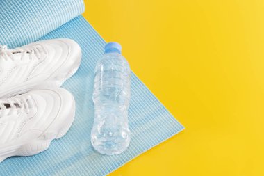 Yoga minderi, spor ayakkabıları, su şişesi, sağlıklı yaşam tarzı kavramı.