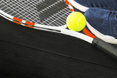 Siyah ahşap arka planda tenis. koşu ayakkabıları, tenis raketi, top,
