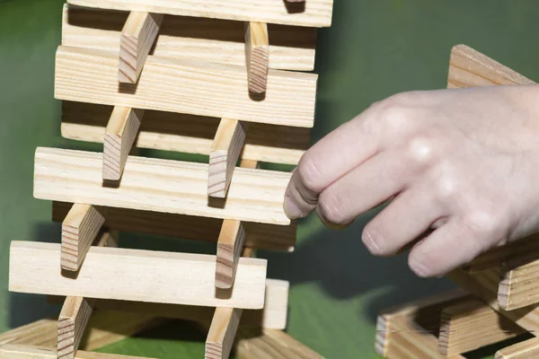 Башня из деревянных блоков и рука человека взять один блок — стоковое фото