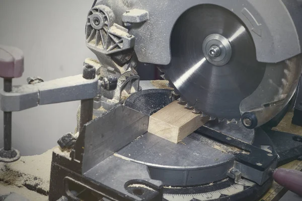 A miter saw making a compound cut through construction lumber. — Stock Photo, Image