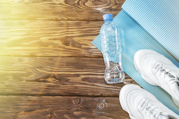 Esterilla de yoga, zapatos deportivos, botella de agua, el concepto de un estilo de vida saludable — Foto de Stock