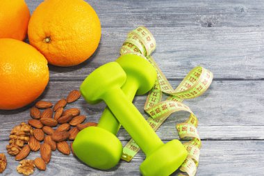 Bir sürü portakal, dambıl, ahşap desenli arka planda mezura. Fitness, spor beslenme.